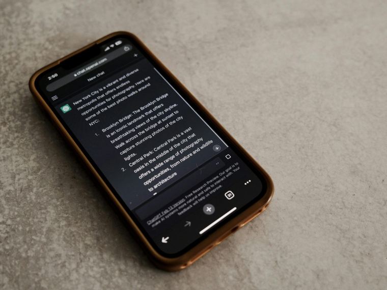 Telefoon op een betonnen ondergrond met een ChatGPT-gesprek in beeld