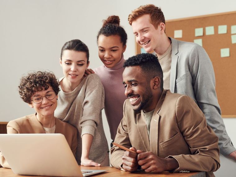 Vijf collega's die samen naar een laptopscherm kijken